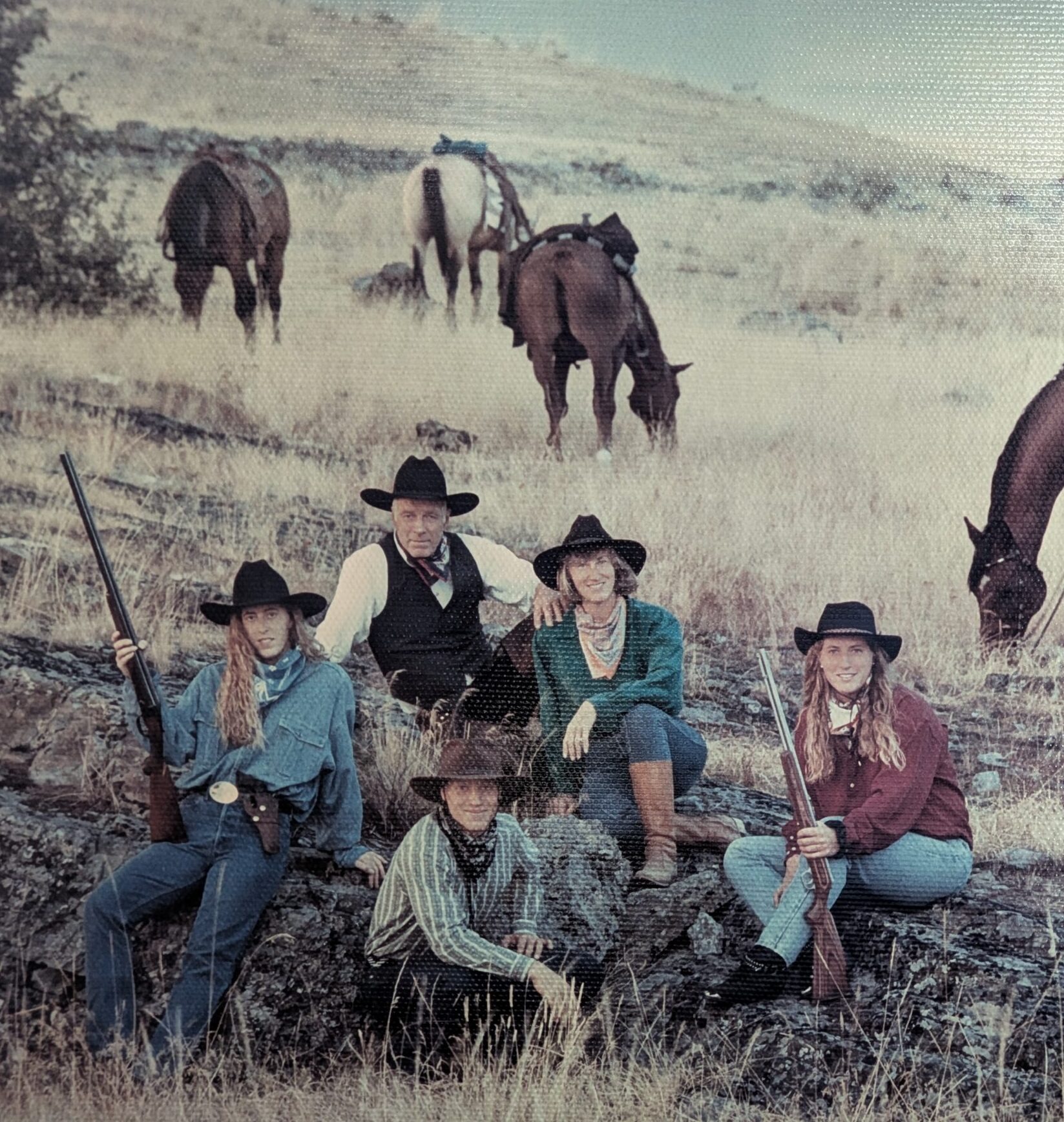 The Binger family sitting in a field with horses behind them.